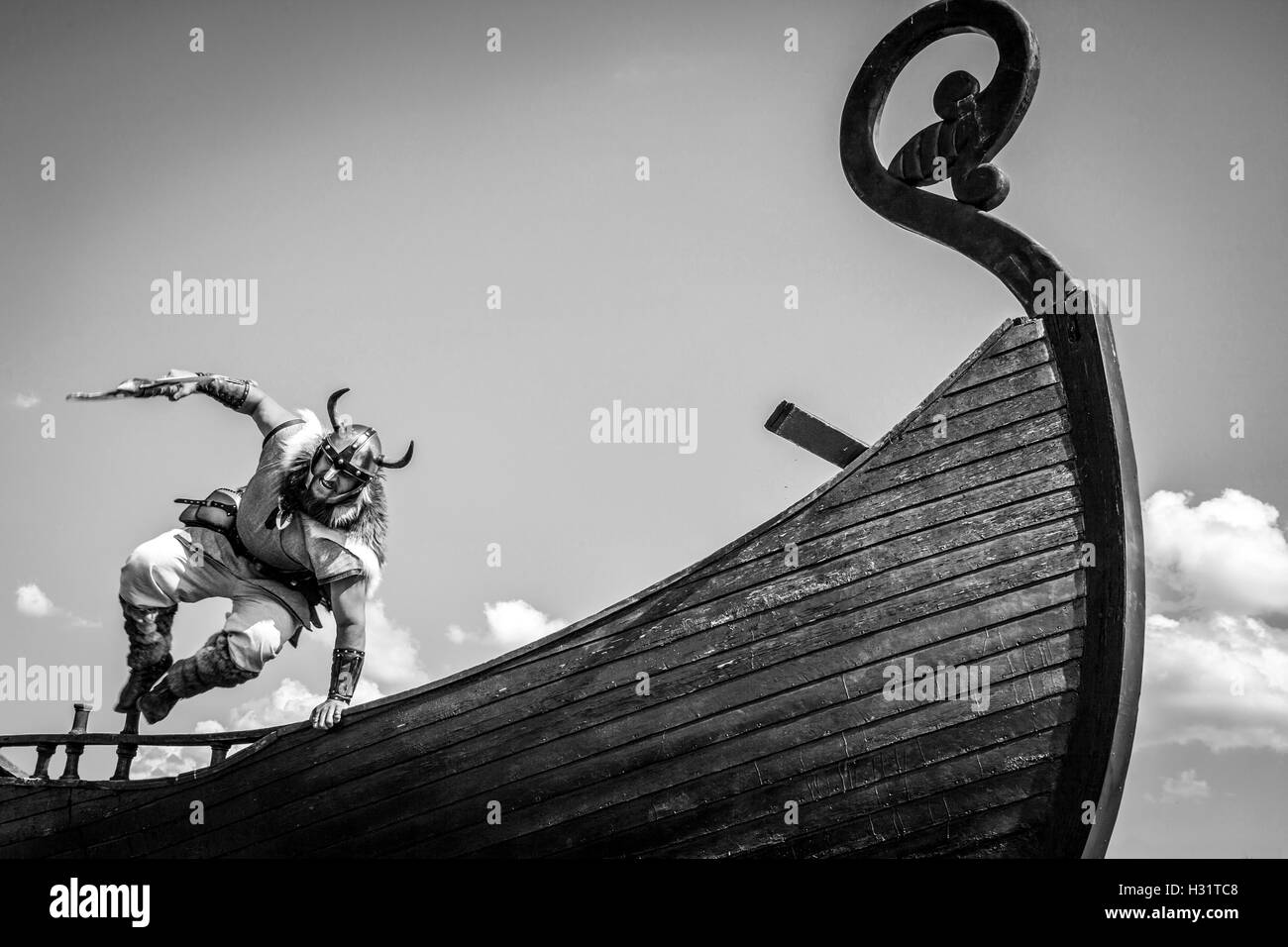 Strong angry bearded Viking with axe jumping from his ship to ...