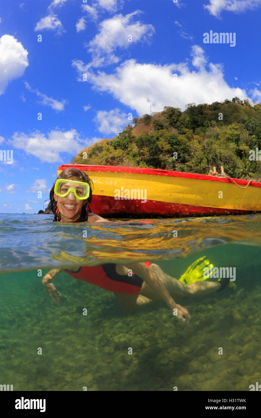 over-under view of happy woman swimming next to colorful boat in front of a tropical island in the Caribbean Photo Copyright © B Stock Photo