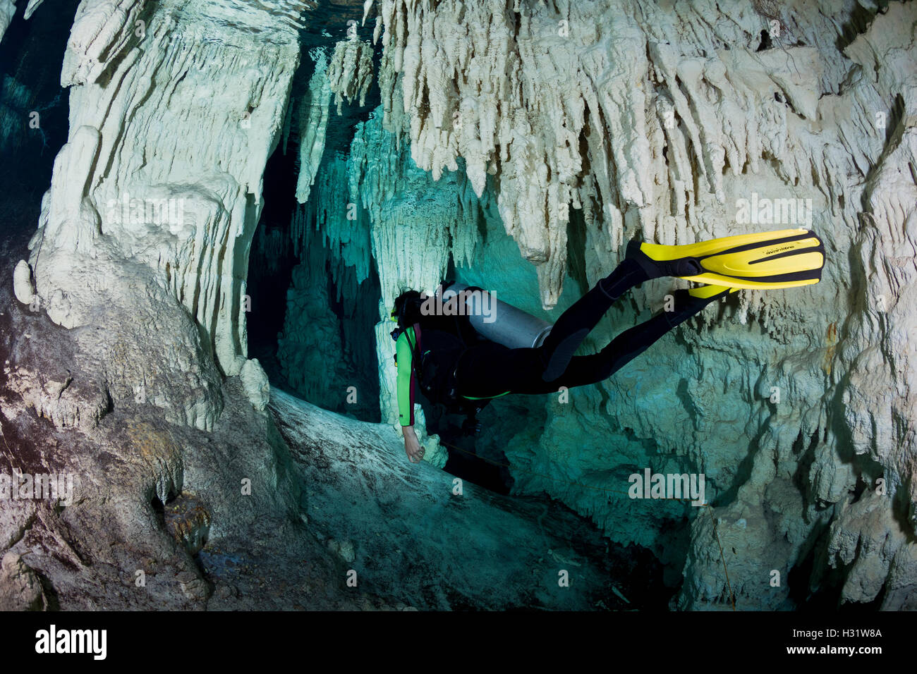 scuba diver (model released) swimming through caverns and tunnels accessed from the surface via a cenote in the jungle. This und Stock Photo