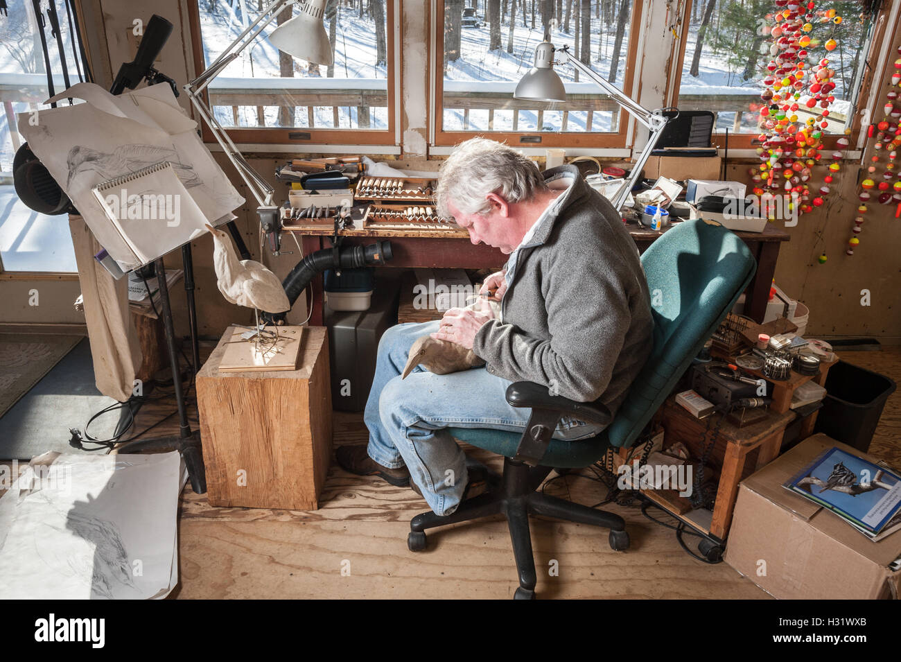 A man working in his studio on a wooden bird carving. Stock Photo