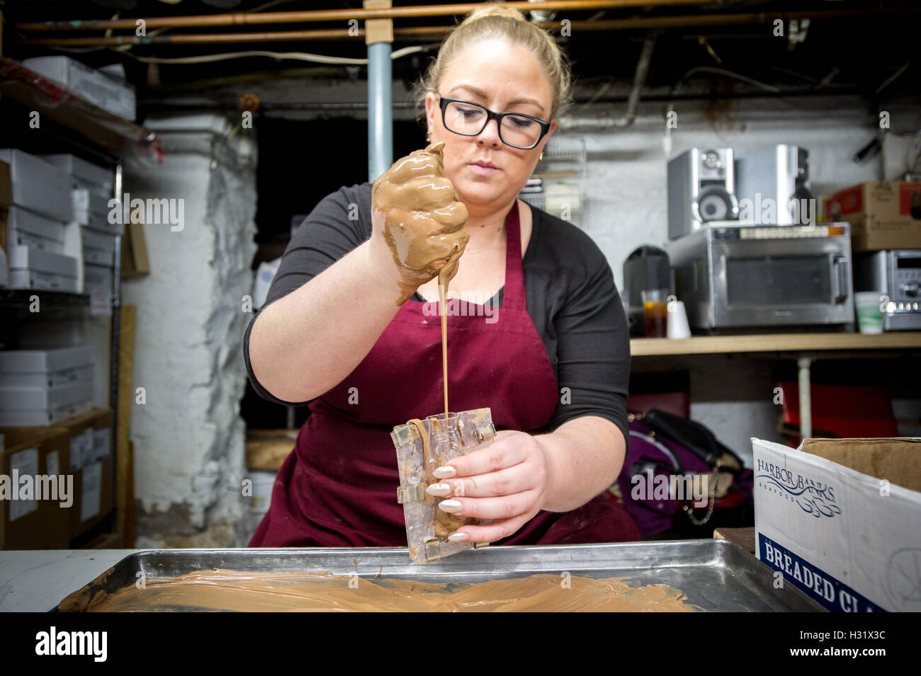 Woman pouring melted chocolate into a plastic mold to make chocolate
