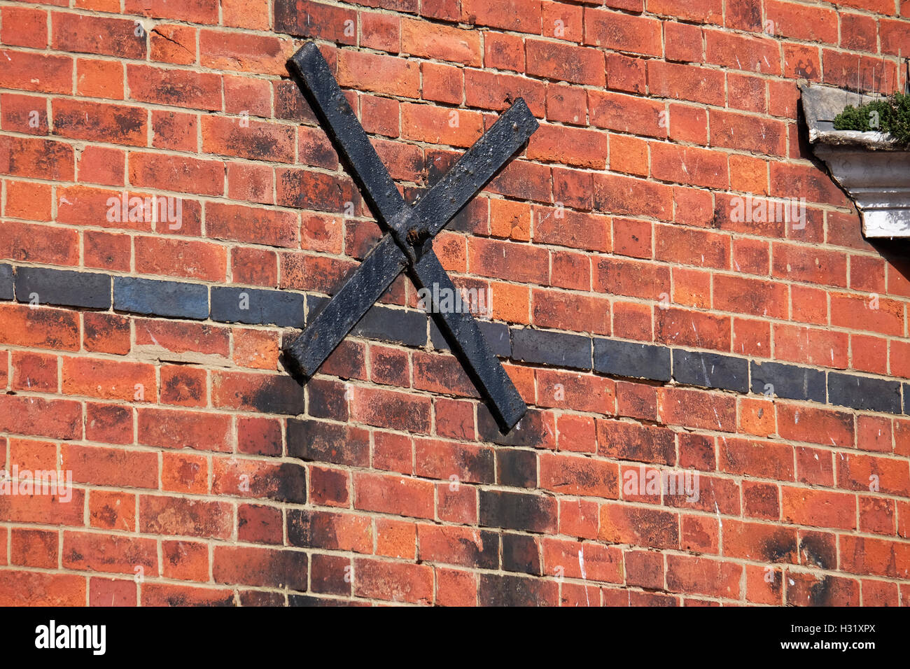 Steel cross on house wall with connecting bar through building to prevent wall bulge and collapse. Stock Photo