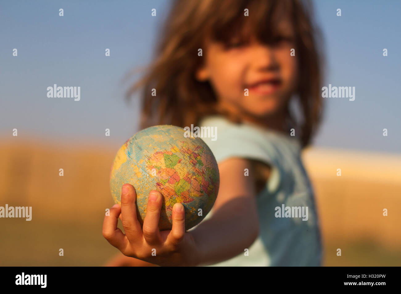 Front view of a child hand holding a damaged toy globe, shallow depth of field Stock Photo