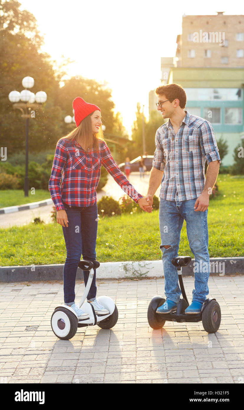 A young couple riding hoverboard - electrical scooter, personal eco transport, gyro scooter, smart balance wheel. New modern tec Stock Photo