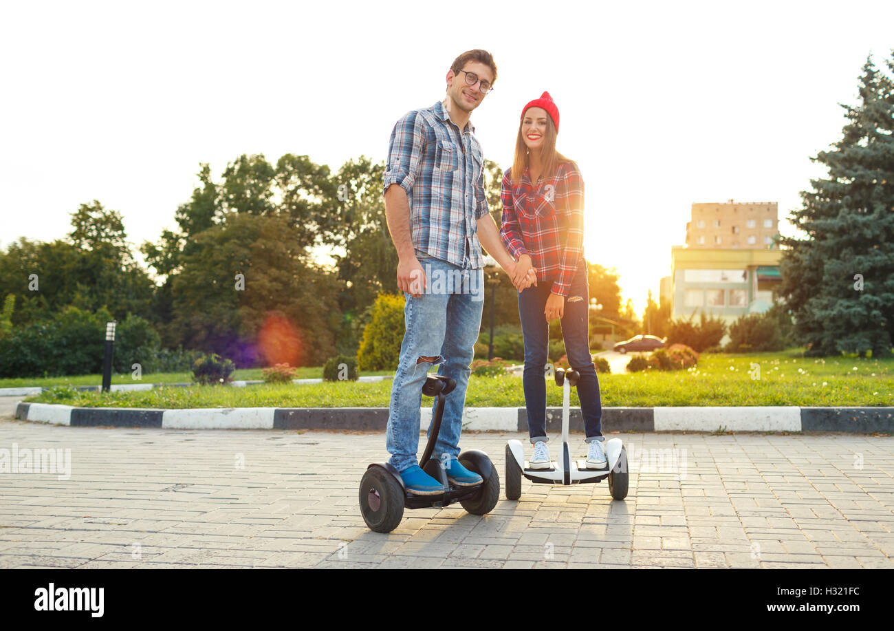 A young couple riding hoverboard - electrical scooter, personal eco transport, gyro scooter, smart balance wheel. New modern tec Stock Photo