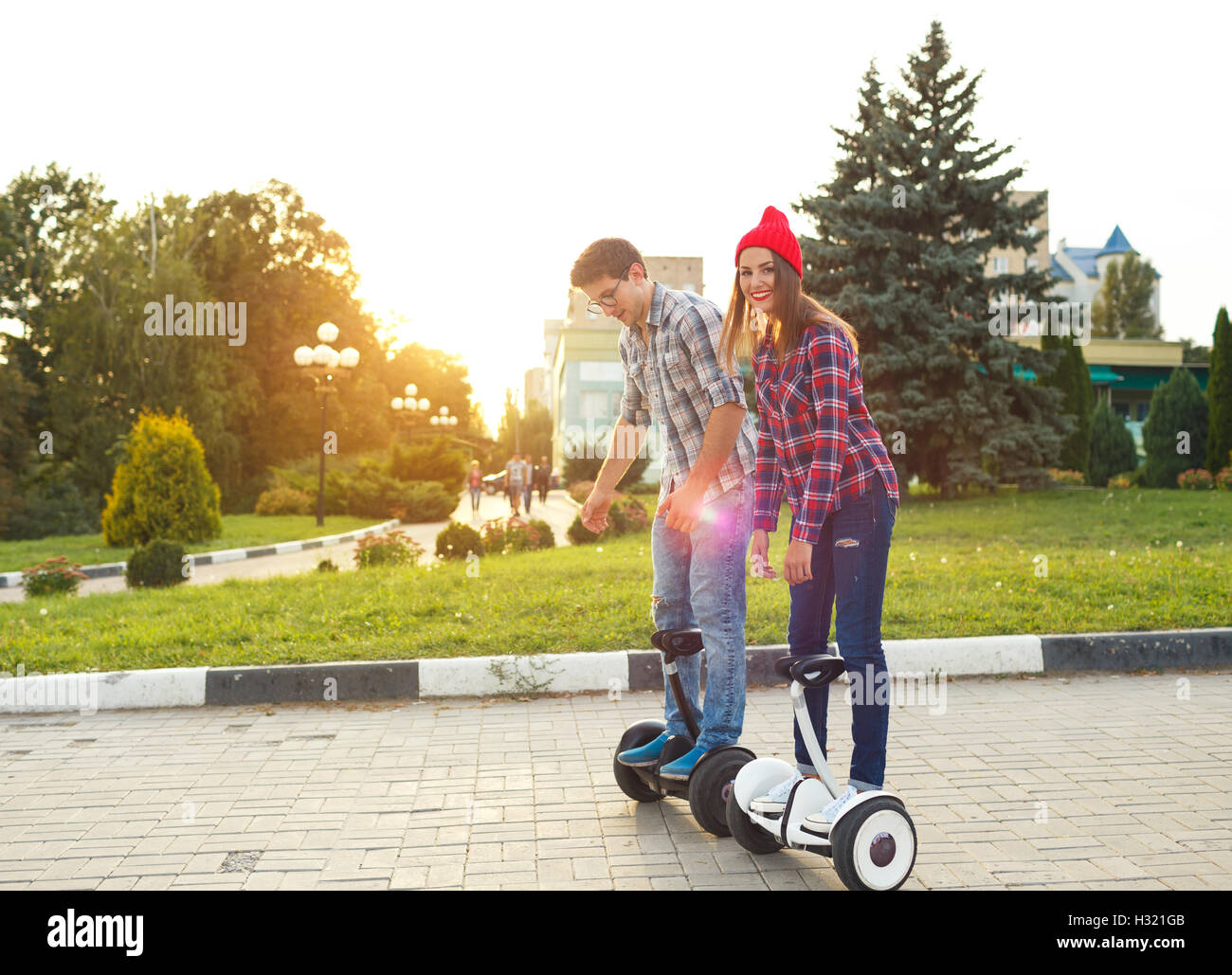 A young couple riding hoverboard - electrical scooter, personal eco transport, gyro scooter, smart balance wheel Stock Photo