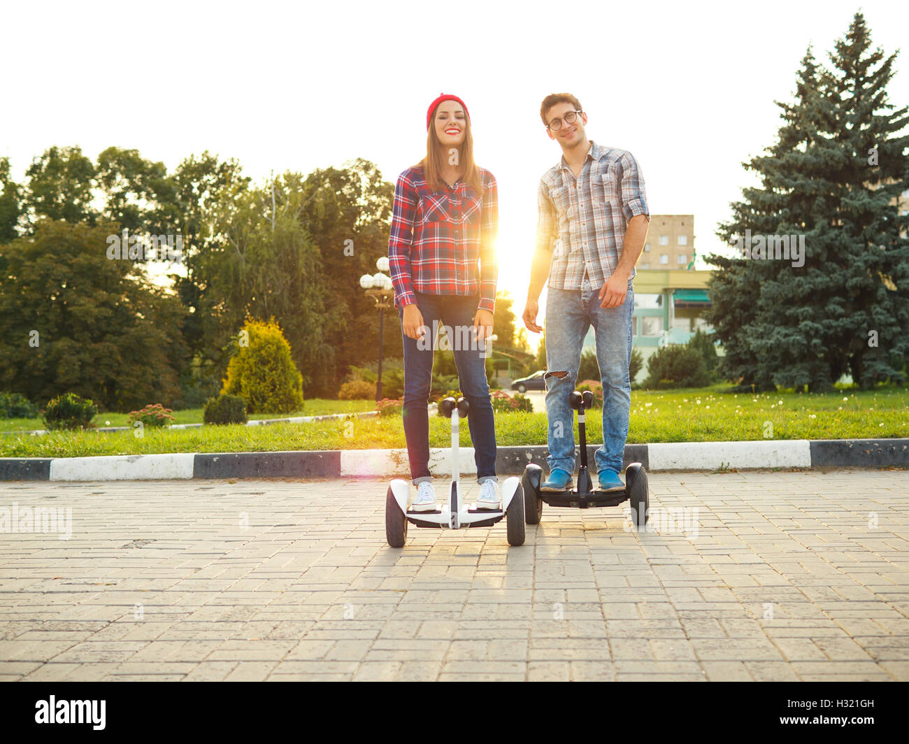 A young couple riding hoverboard - electrical scooter, personal eco transport, gyro scooter, smart balance wheel Stock Photo