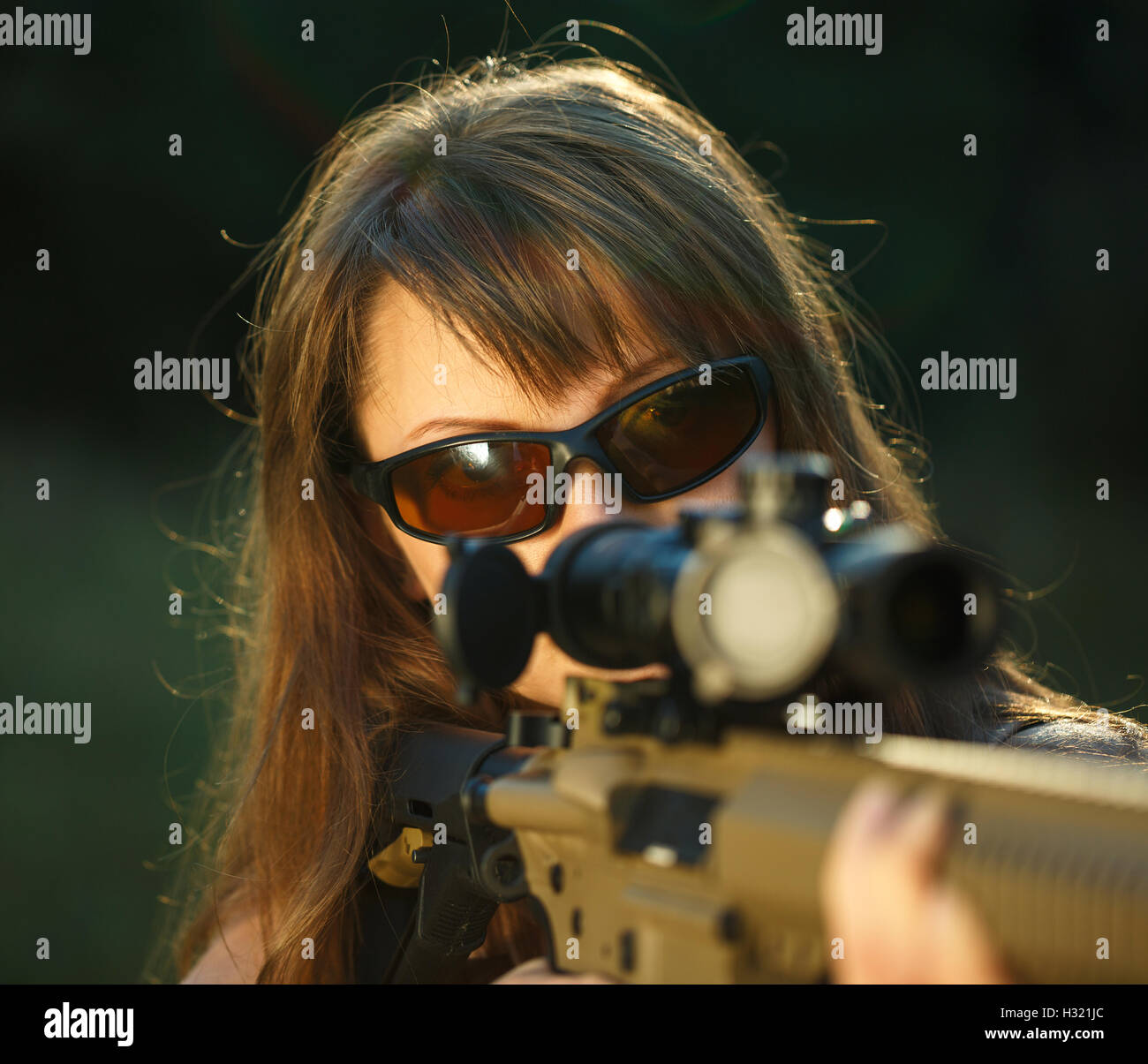 A young girl with a gun for trap shooting and shooting glasses aiming