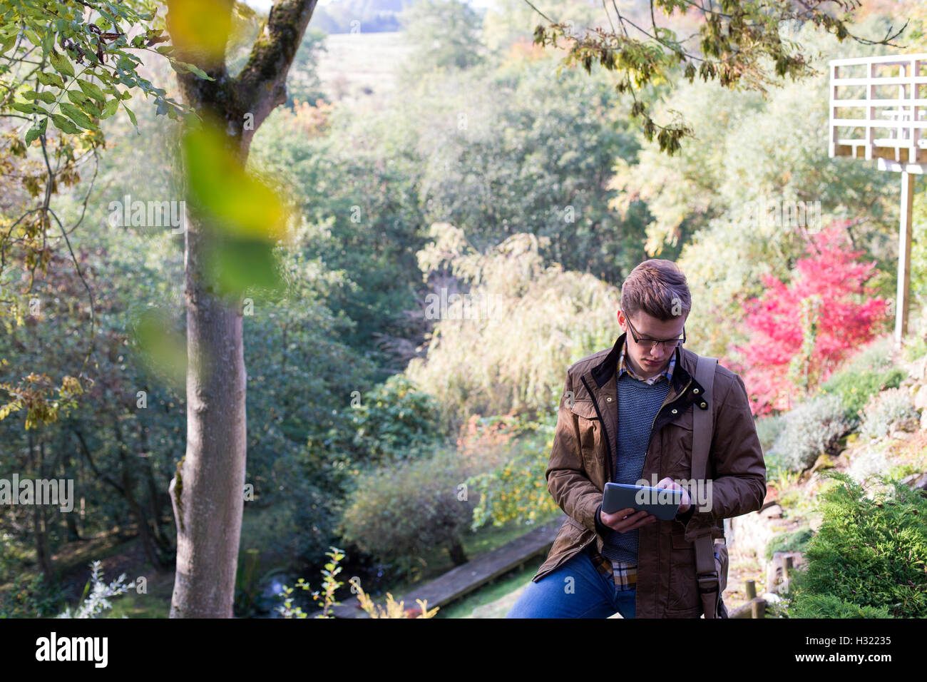 Young man analysing nature. He is using a digital tablet for research. Stock Photo