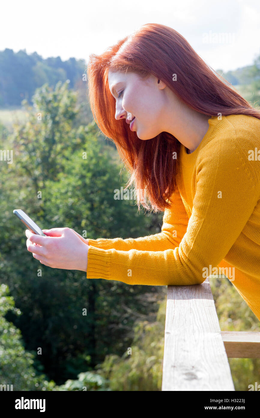 Young woman using her smart phone on her garden balcony. Stock Photo