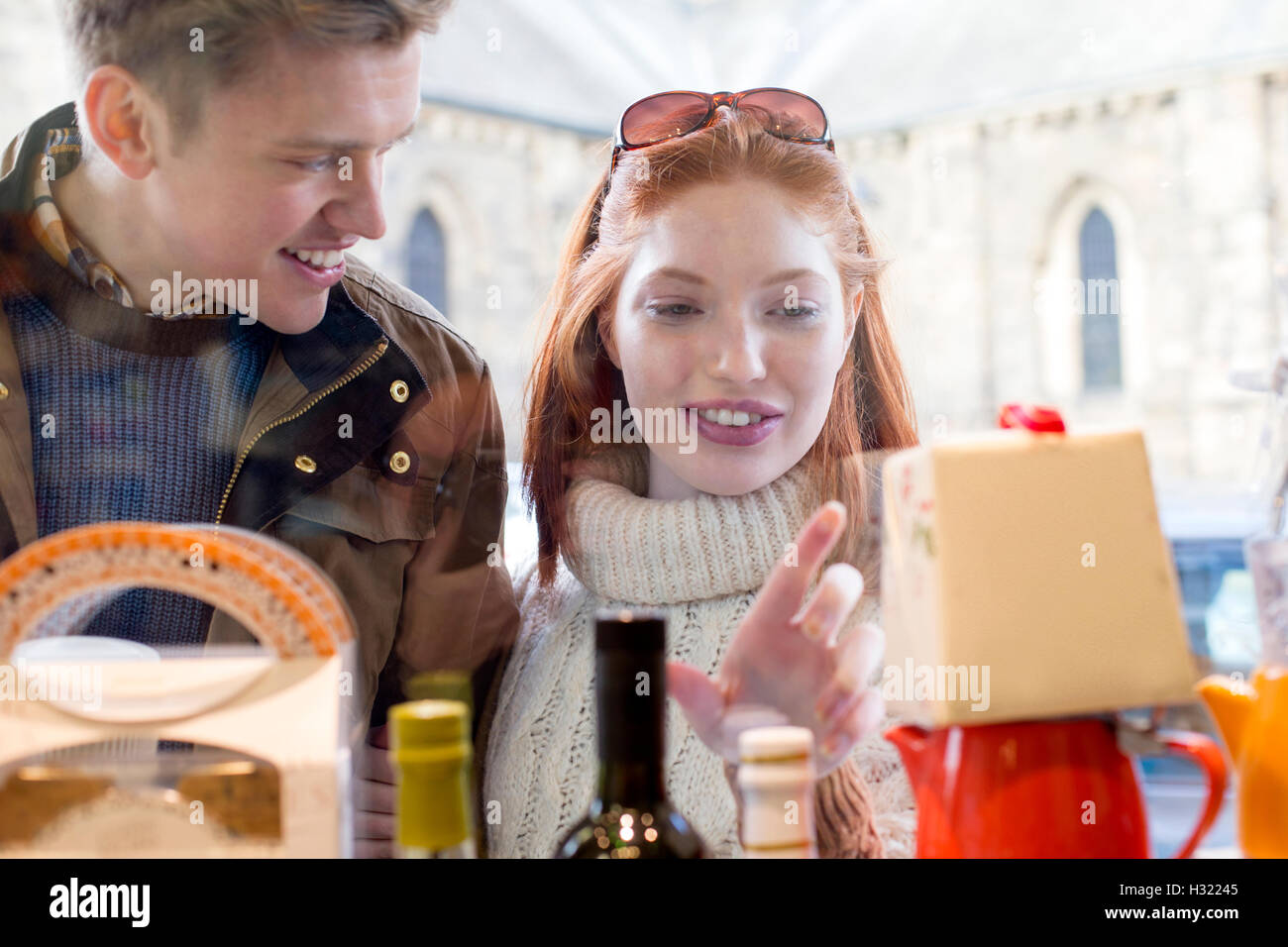 Young couple looking in a farm shop window at wine and cake. Stock Photo