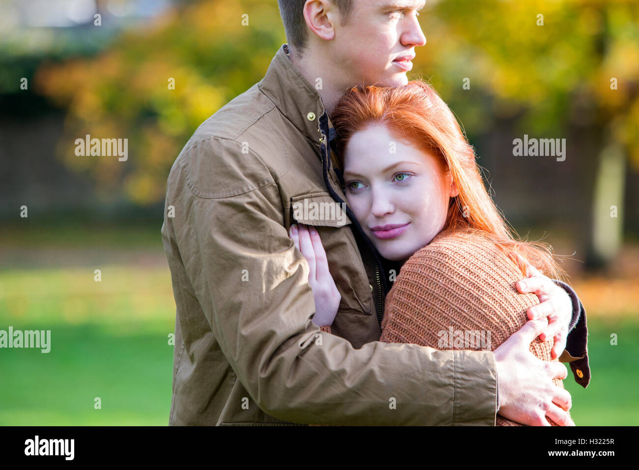 young couple enjoying a cuddle in a park during Autumn. Stock Photo