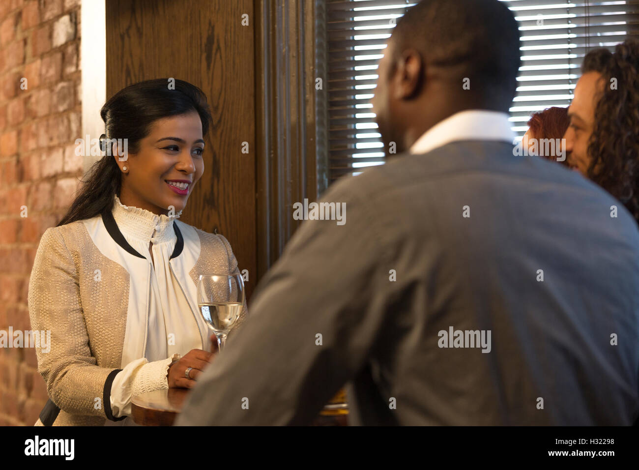 Four friends are drinking wine and talking in a bar. Stock Photo