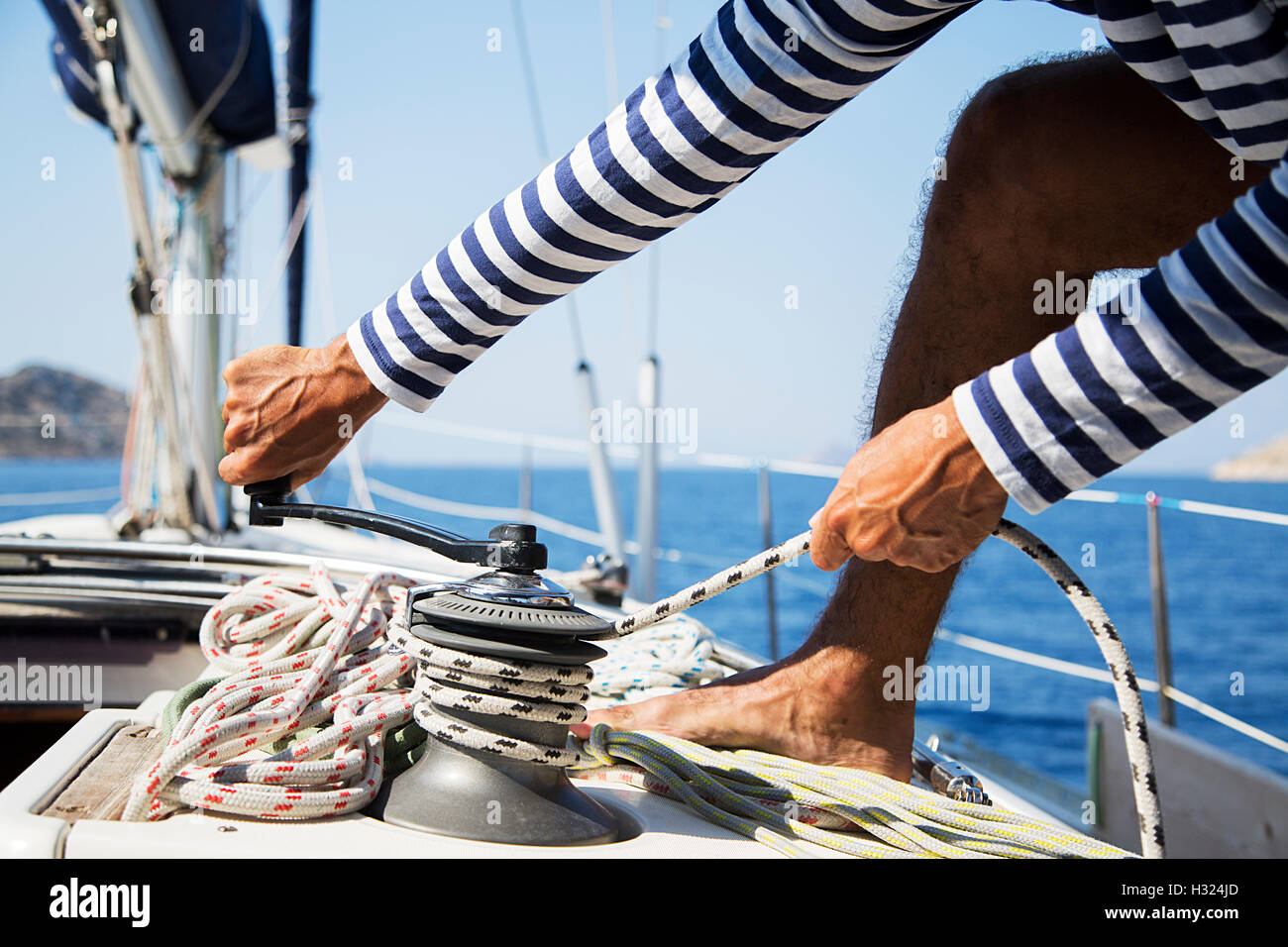 Young handsome sailor pulling rope on sailboat Stock Photo