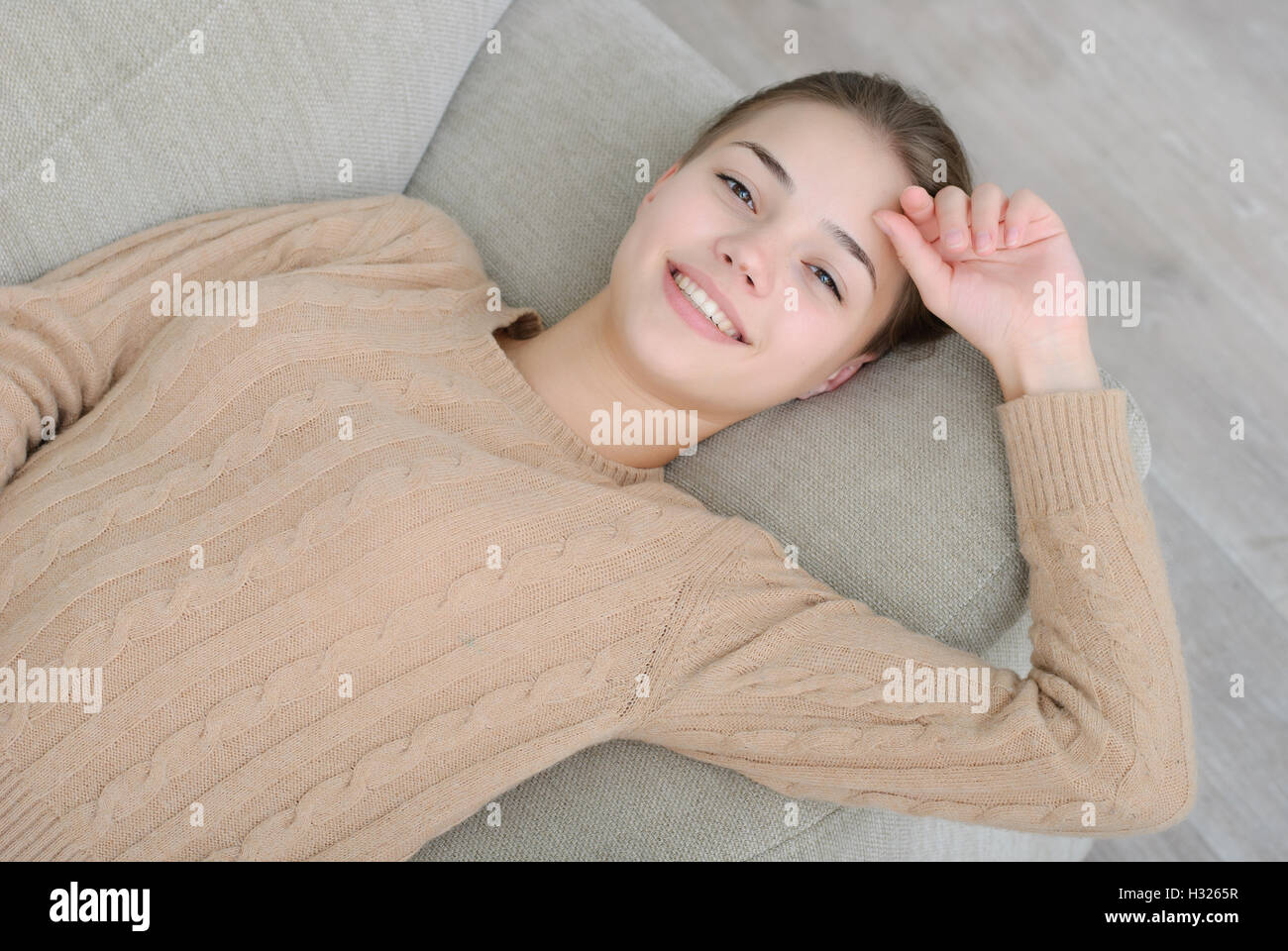 smiling young woman lying on couch Stock Photo - Alamy