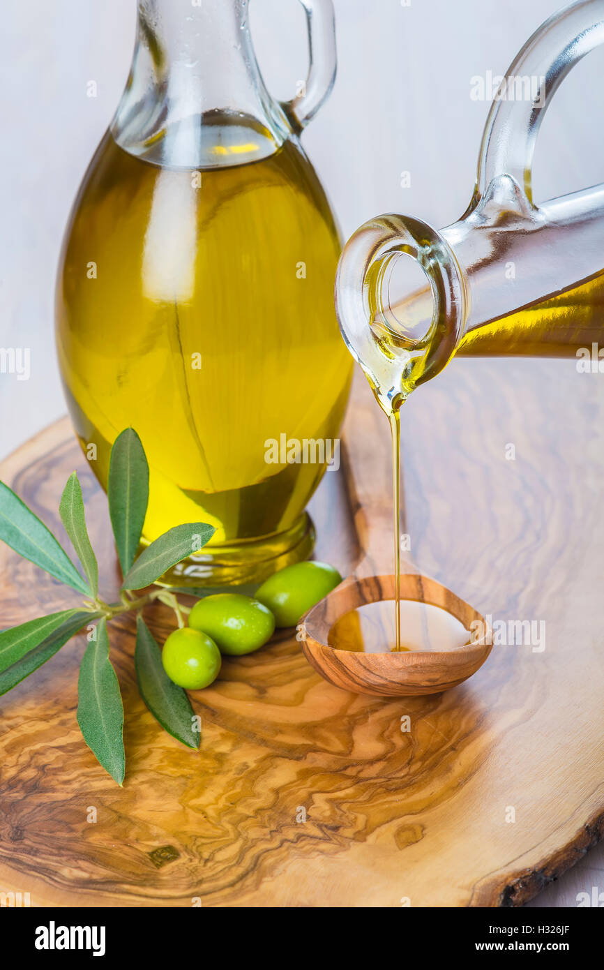 Bottle pouring virgin extra olive oil on a wooden spoon Stock Photo - Alamy