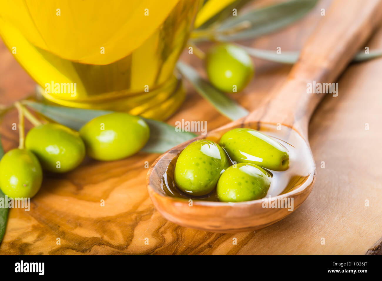 Green olives and virgin olive oil on a wooden spoon Stock Photo - Alamy
