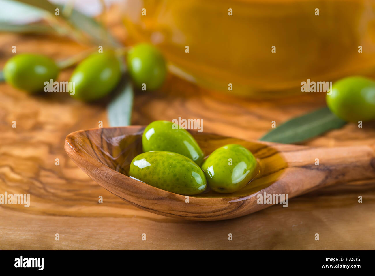 Green olives and virgin olive oil on a wooden spoon Stock Photo - Alamy