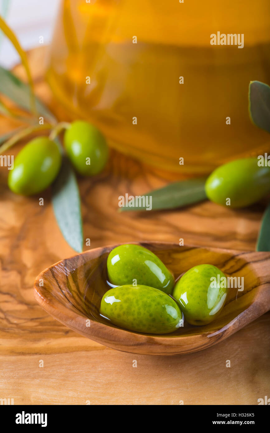 Green olives and virgin olive oil on a wooden spoon Stock Photo - Alamy