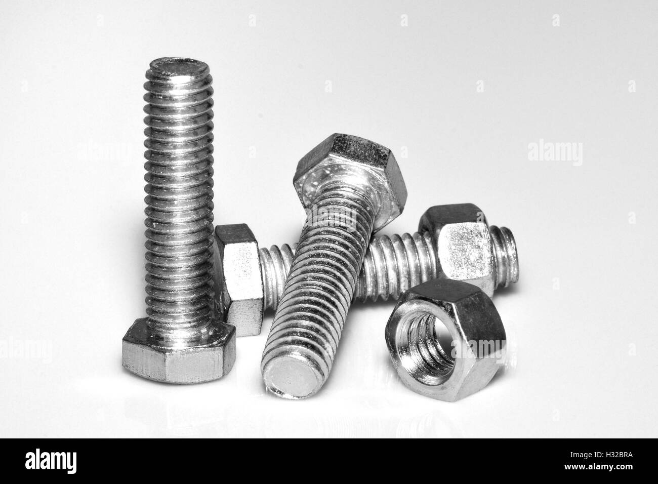 Steel bolts and nuts on white background close-up. B&W Stock Photo