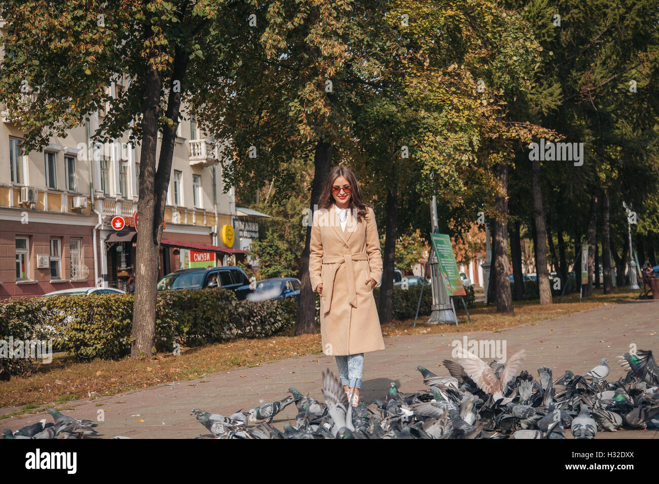 Girl with doves in a coat on a city alley Stock Photo