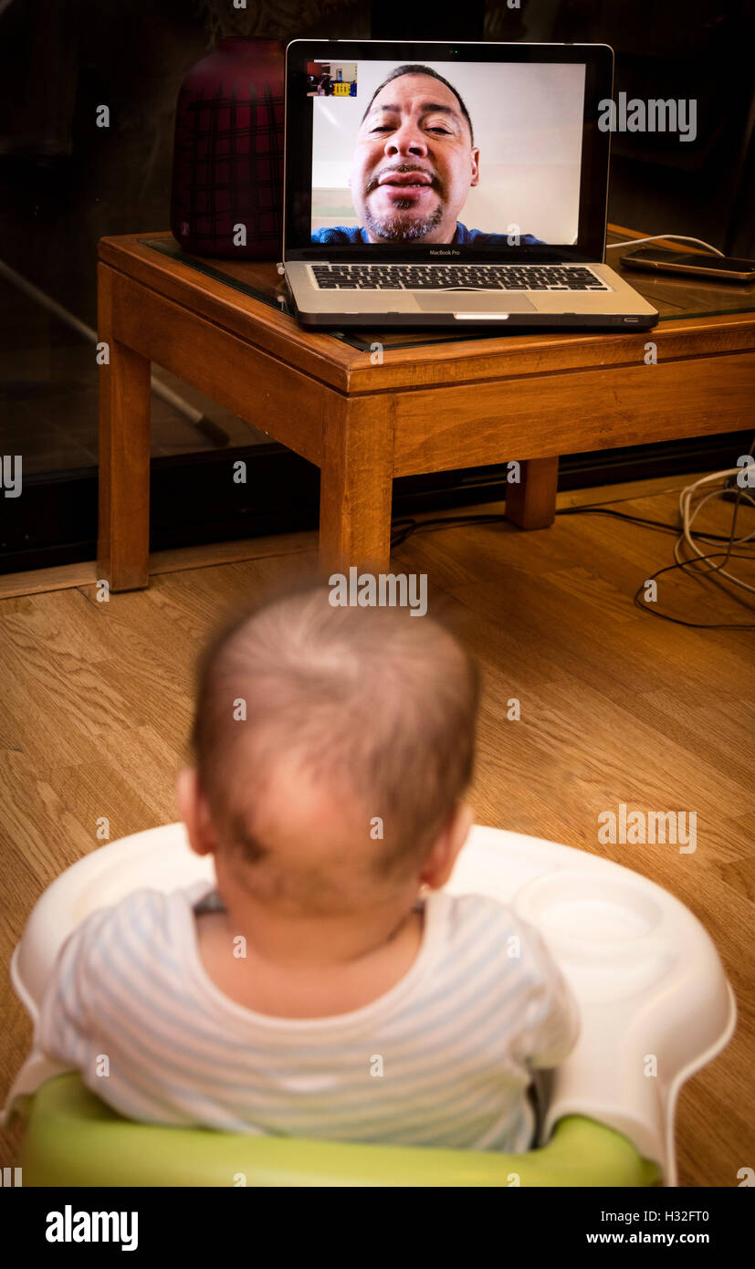 baby watching grandfather on Skype on computer Stock Photo