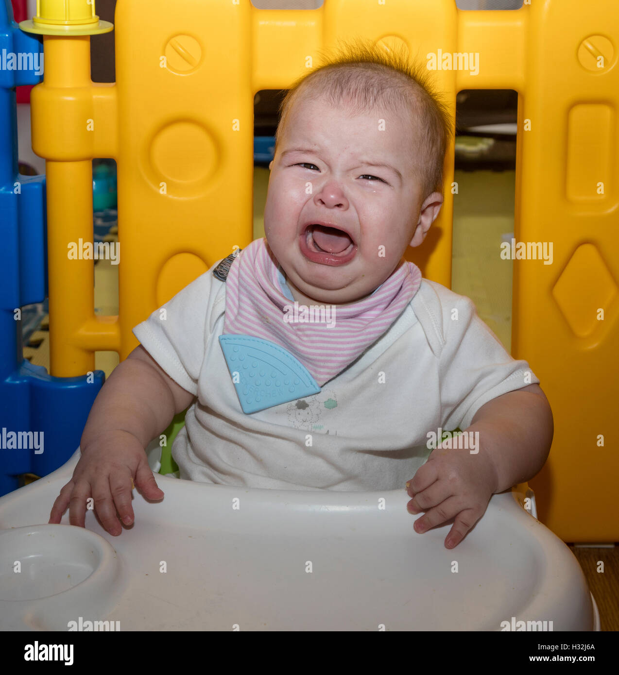 baby sitting in bumbo seat with tray, crying Stock Photo