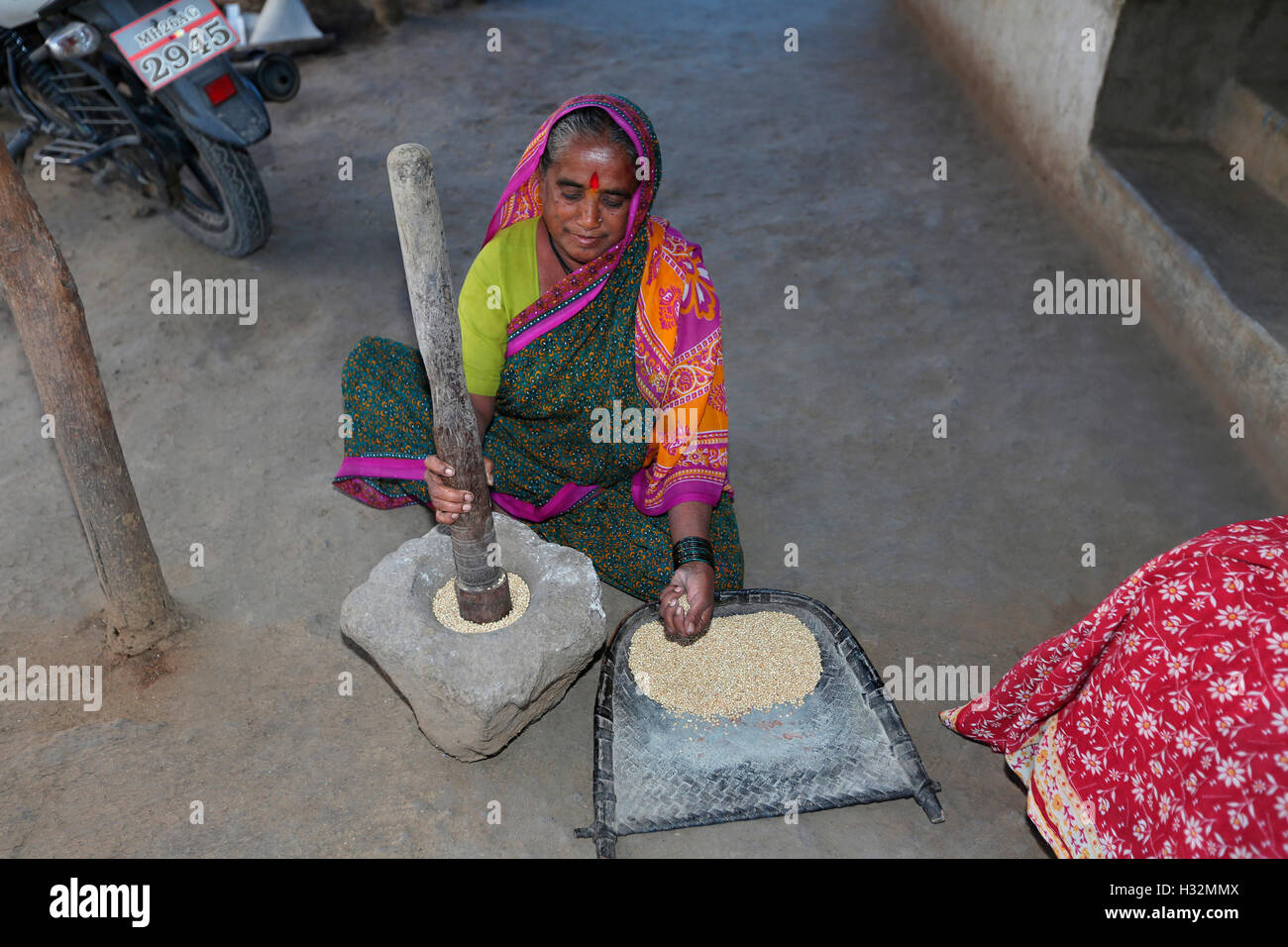 Woman pounding grains. ANDH TRIBE, Injegaon village, Maharashtra, India Stock Photo