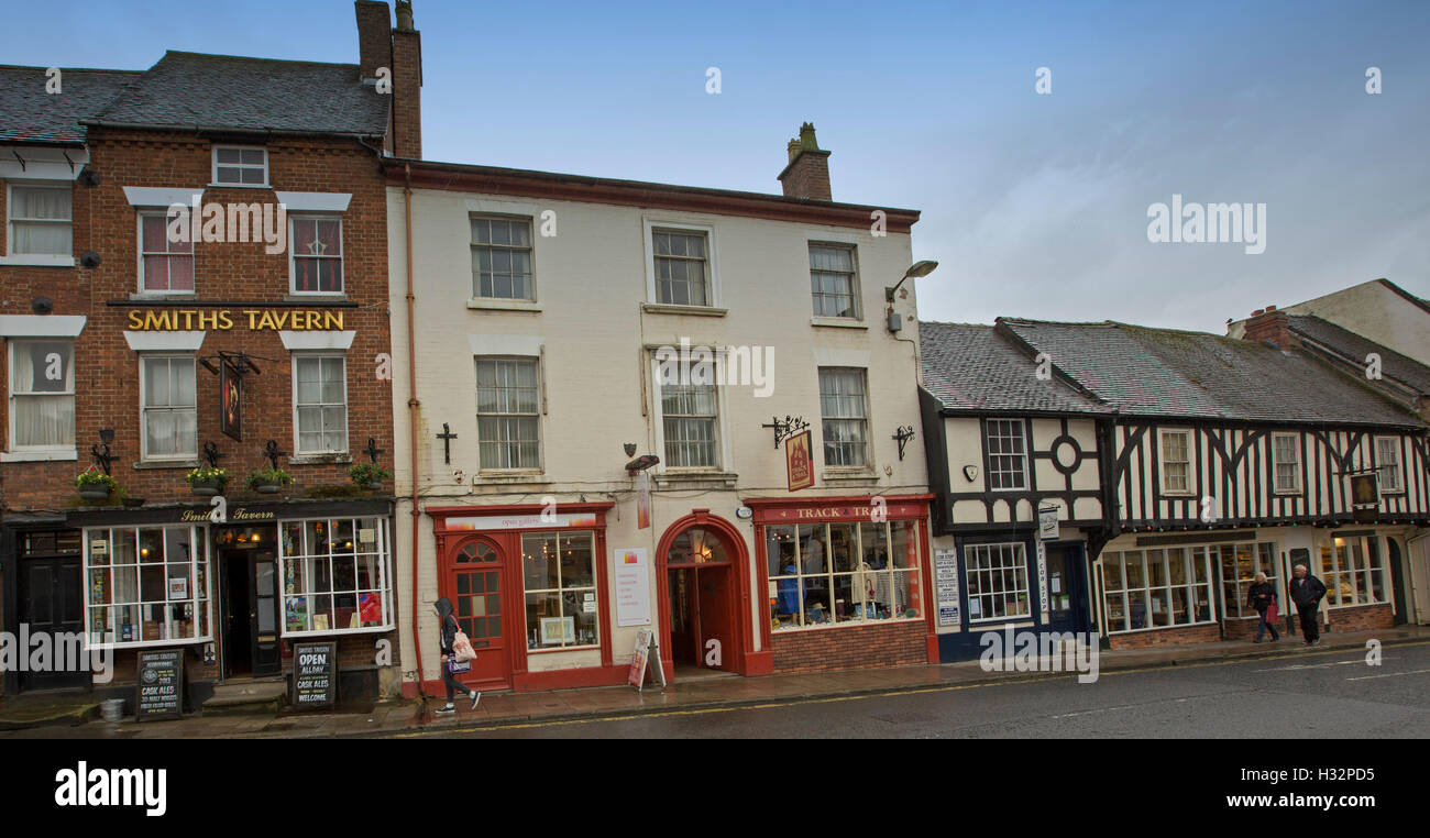 Street in English town of Ashbourne with historic buildings including shops, cafes, & tavern with people walking on footpath Stock Photo