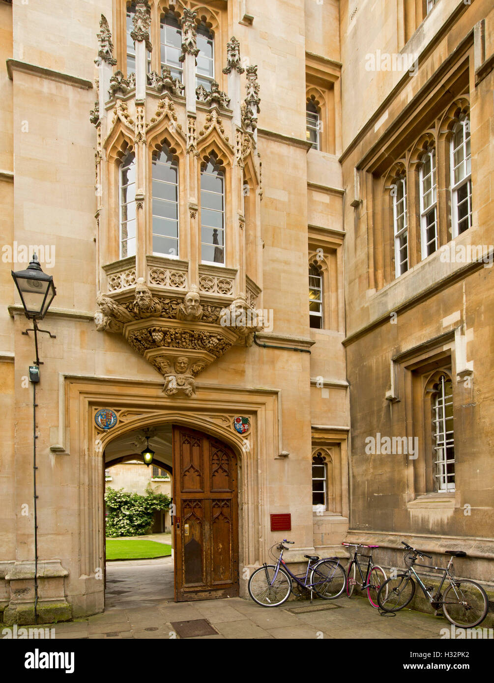 Ornate entrance to historic building with gothic style bay window, arched wooden door & bicycles leaning on wall in Oxford UK Stock Photo