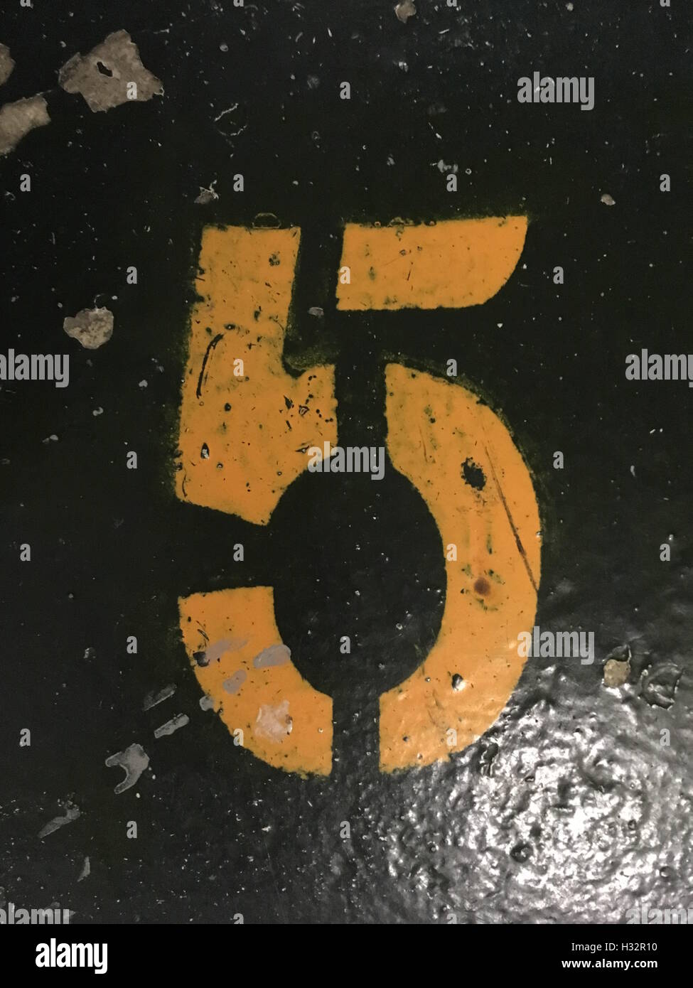 Number 5 painted in a stencil style in orange yellow color on the floor Stock Photo
