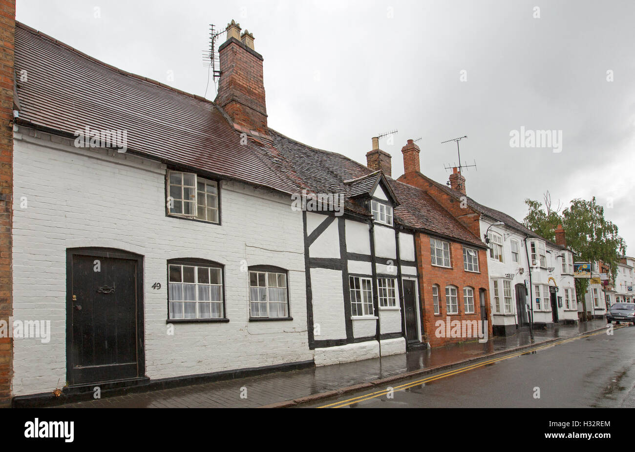 Row of historic black and white medieval buildings beside more modern red brick building in Stratford-upon-Avon, England Stock Photo