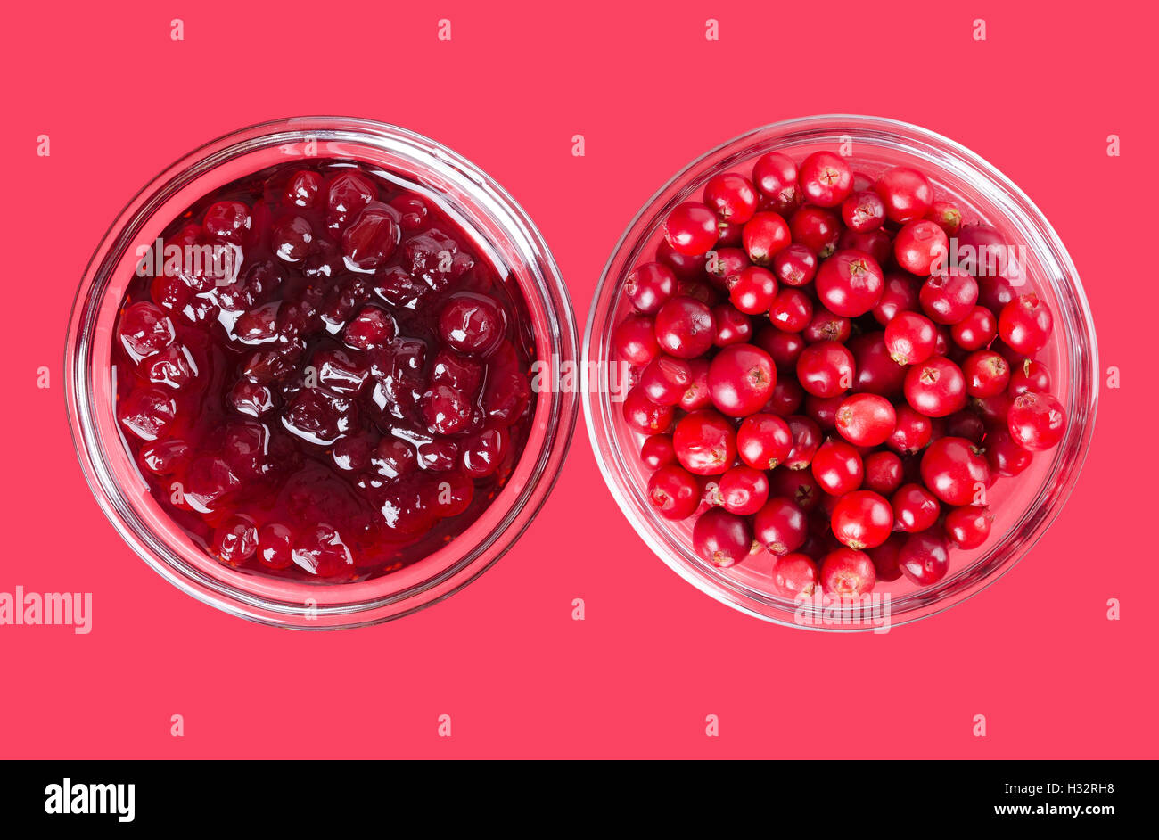 Lingonberry jam and lingonberries in glass bowls over pink. Fresh red fruits of Vaccinium vitis-idaea, also mountain cranberries Stock Photo