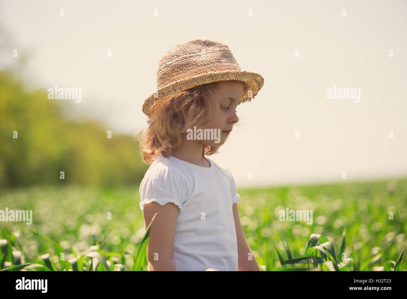 Little girl in straw hat walking through field, summer outdoor Stock Photo