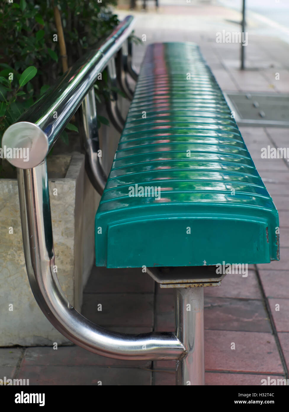 closeup shot of metallic bus stop bench painted in green Stock Photo