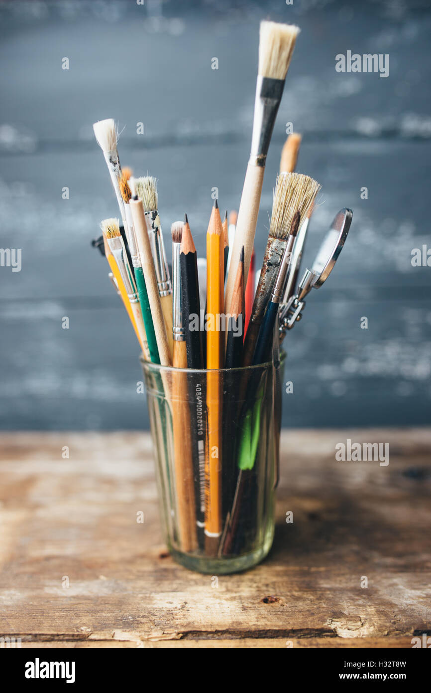 Old used small paint brushes on brushed metal texture background