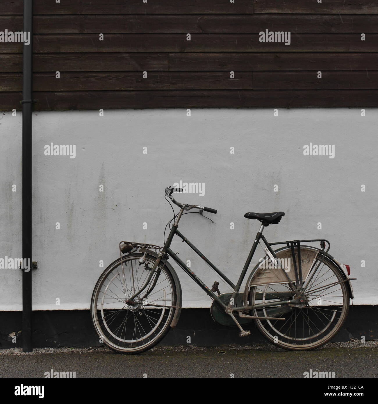 old fashioned ladies bicycle , by white painted wall and weatherboard
