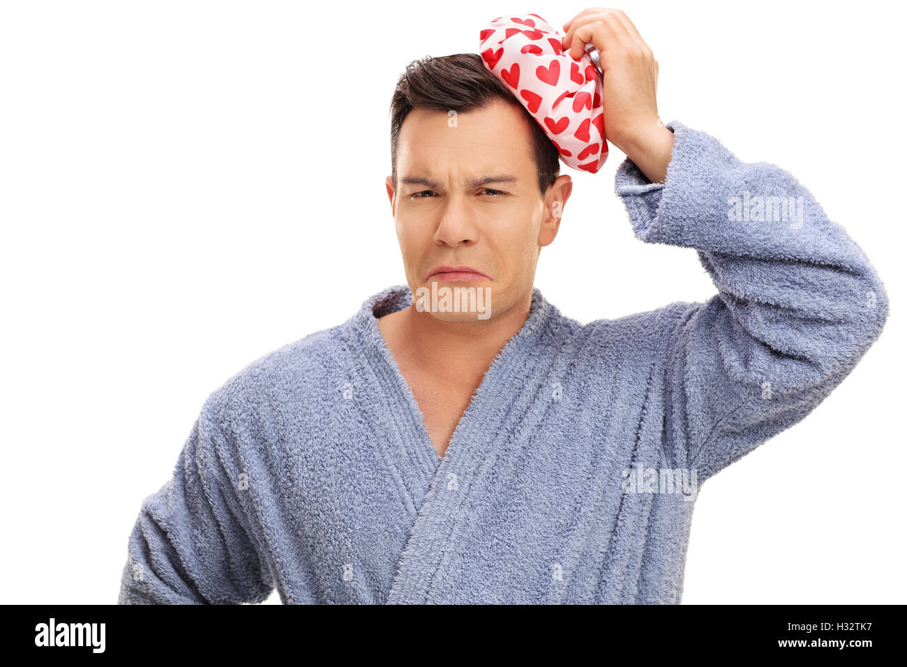 Young man in a bathrobe having a headache and holding an ice pack isolated on white background Stock Photo
