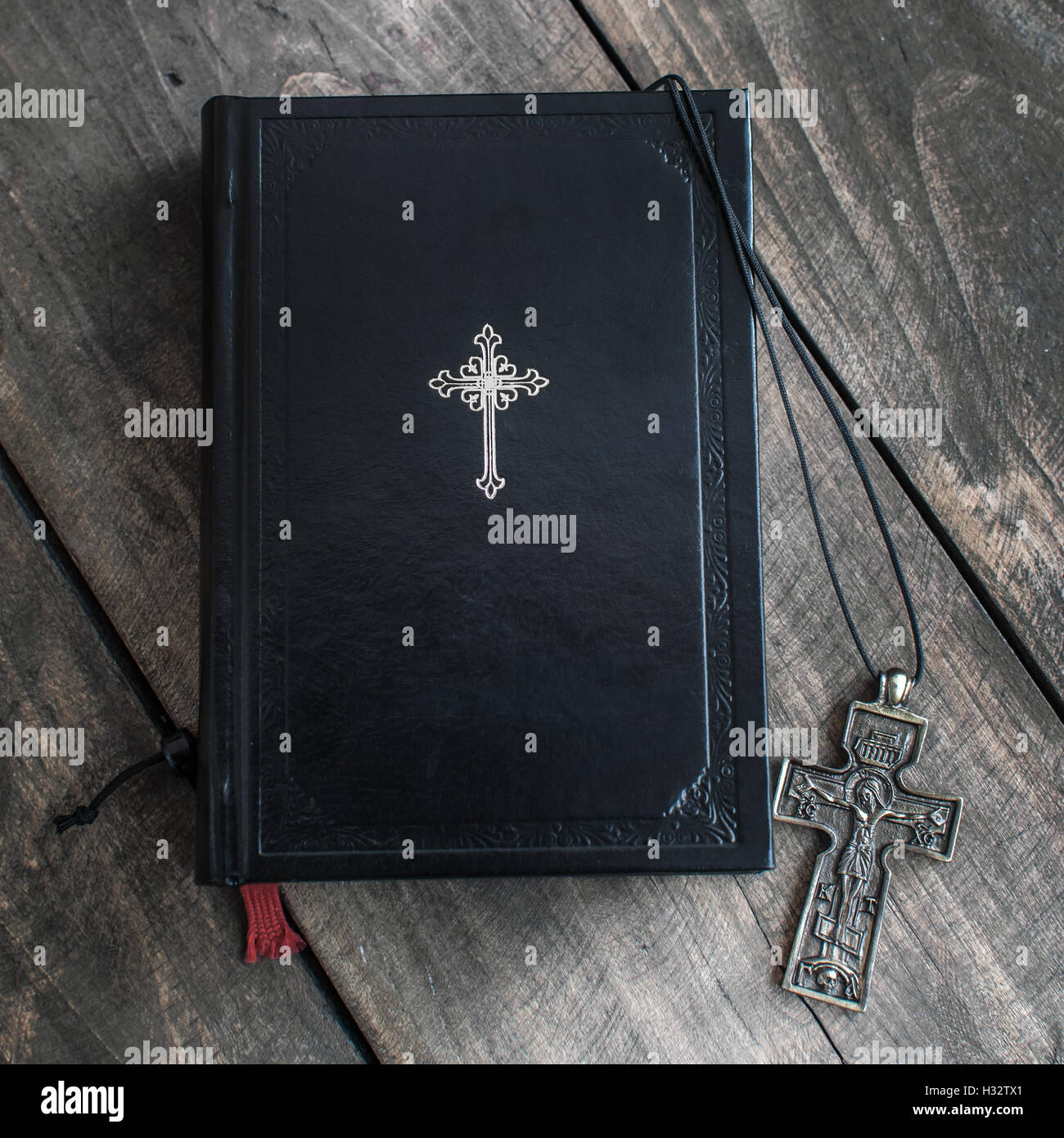 Christian cross necklace next to holy Bible, from above Stock Photo