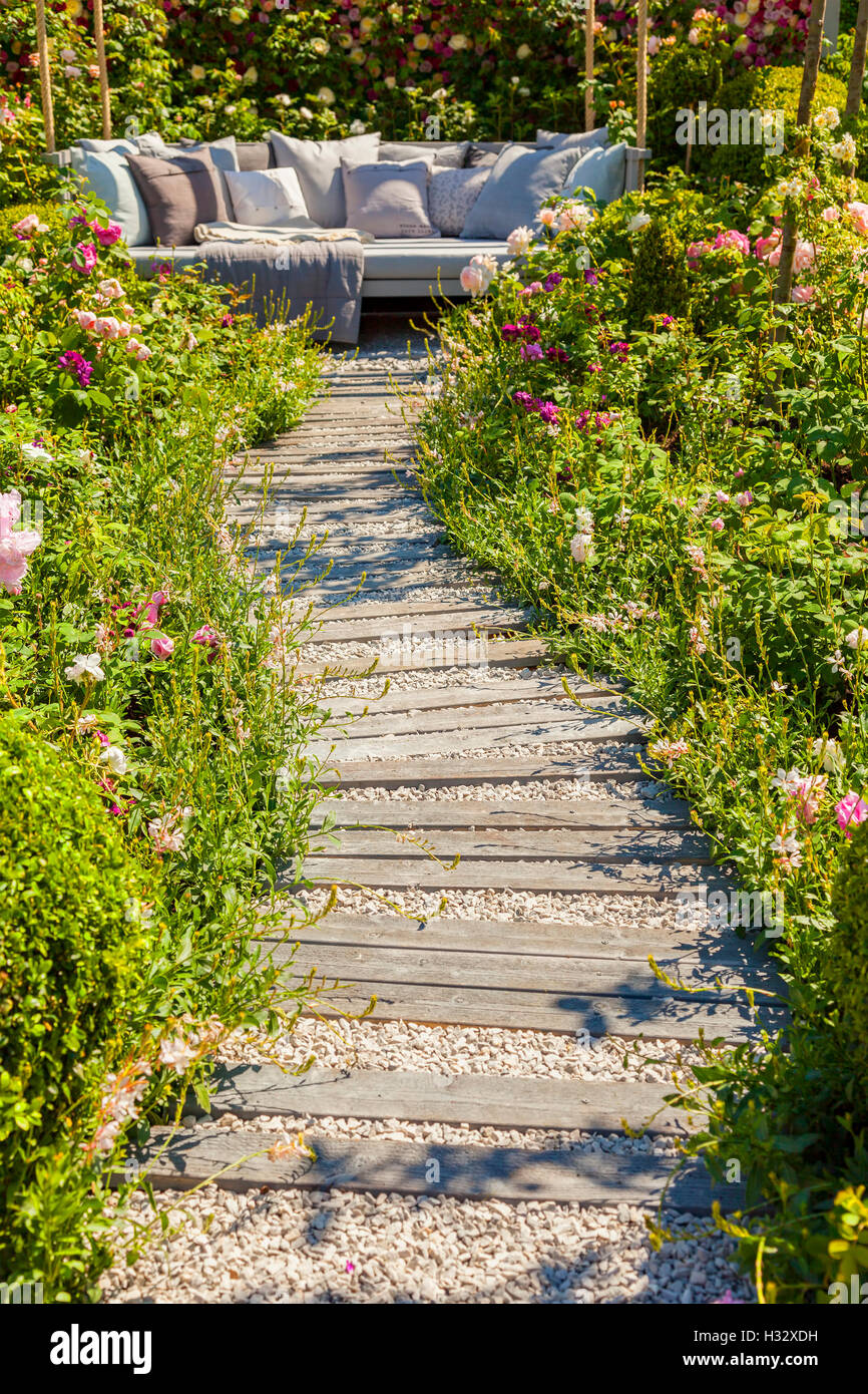 Garden path leading to comfy seating area. Stock Photo