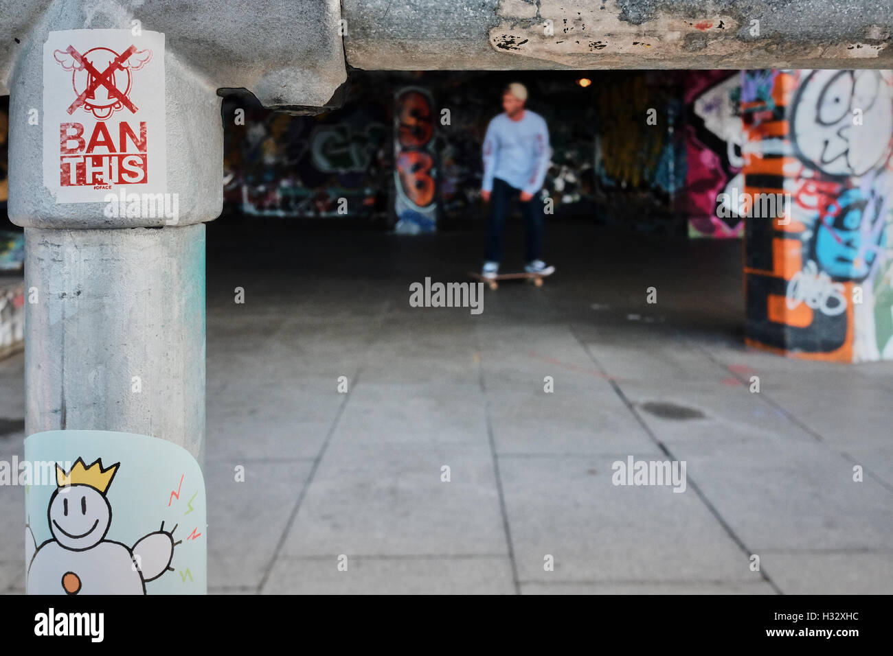 Ban This sign on a railing with out of focus skateboarder and graffiti in the background Stock Photo