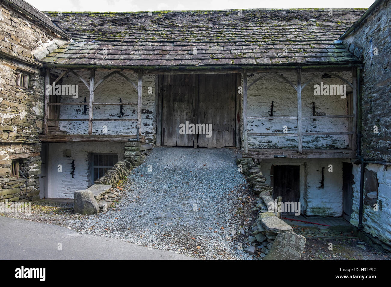 An very old stone farm building with broken windows and wooden doors. Stock Photo