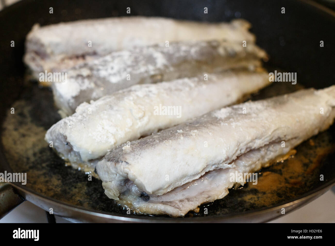 Fried hake fish fillet in a frying pan at kitchen Stock Photo Alamy