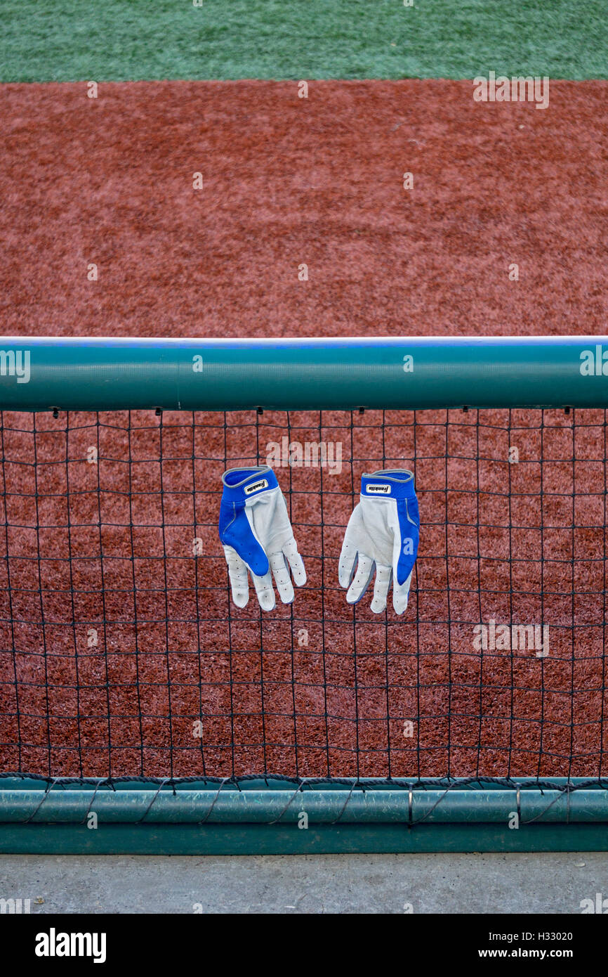 Baseball hitting gloves hanging on a fence near a dugout at MCU Park in Coney Island, Brooklyn, NY at the World Baseball Classic Stock Photo