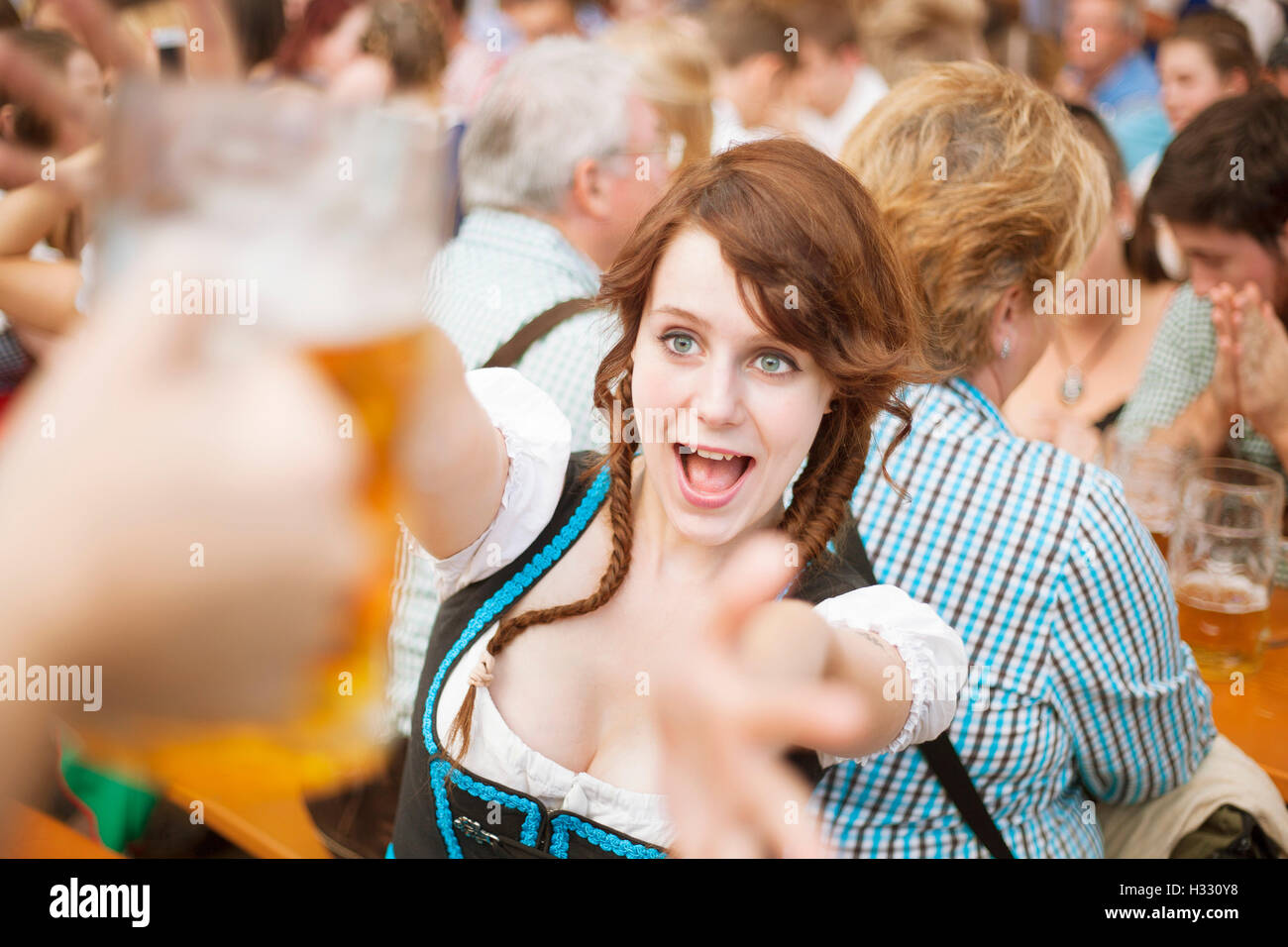 Excited girl reaches for a mug of beer at Oktoberfest Stock Photo