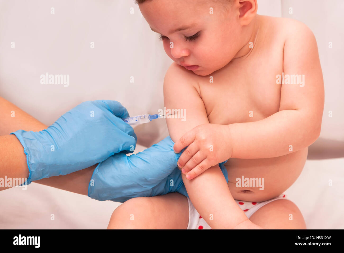 Close-up shot of pediatrician giving a one year baby girl intramuscular injection in arm Stock Photo
