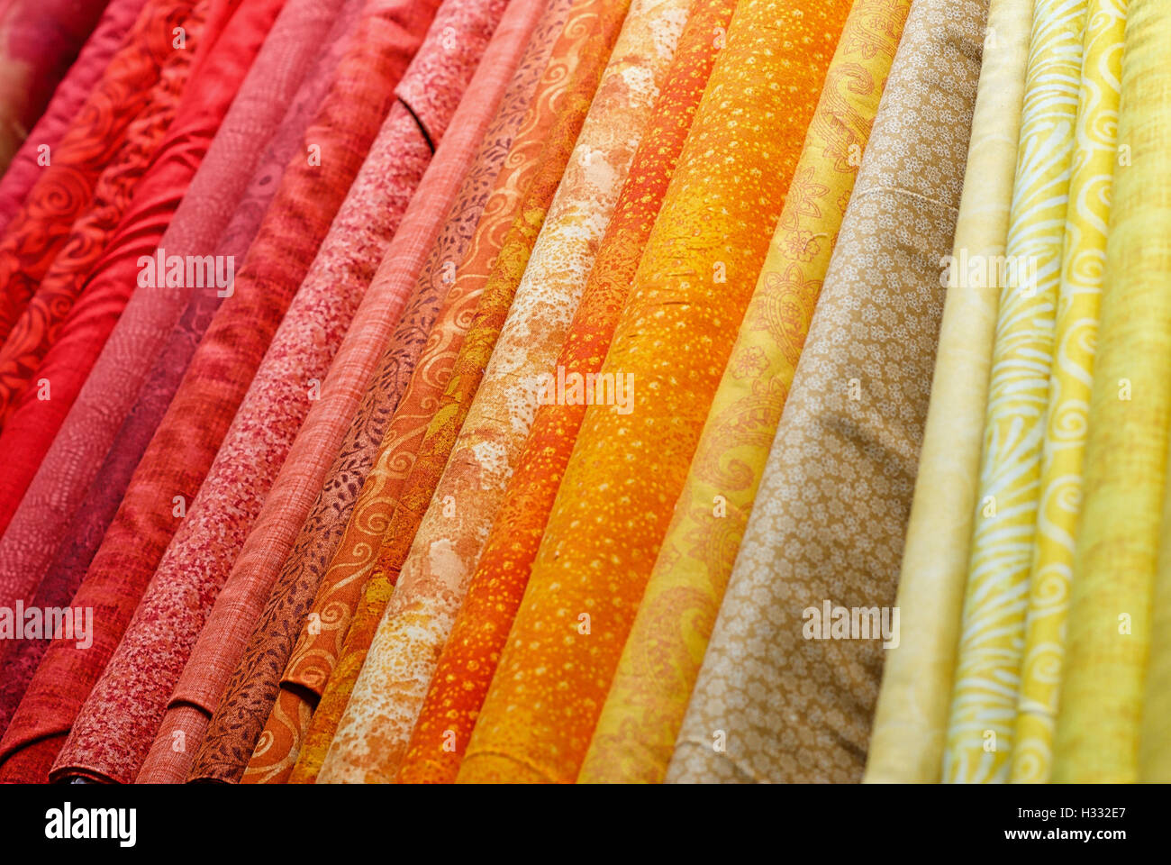 Bolts of colorful fabrics lined up for sale in a variety of styles, patterns, and colors. Stock Photo