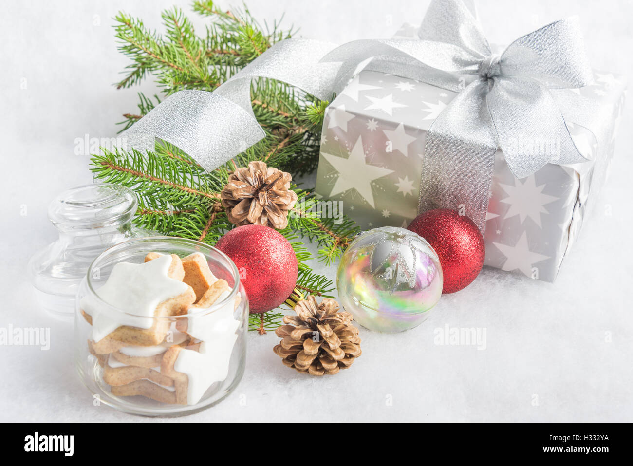Christmas gift box in silver wrapping paper  over a white fluffy background. A jar full of star cookies and christmas decoration Stock Photo