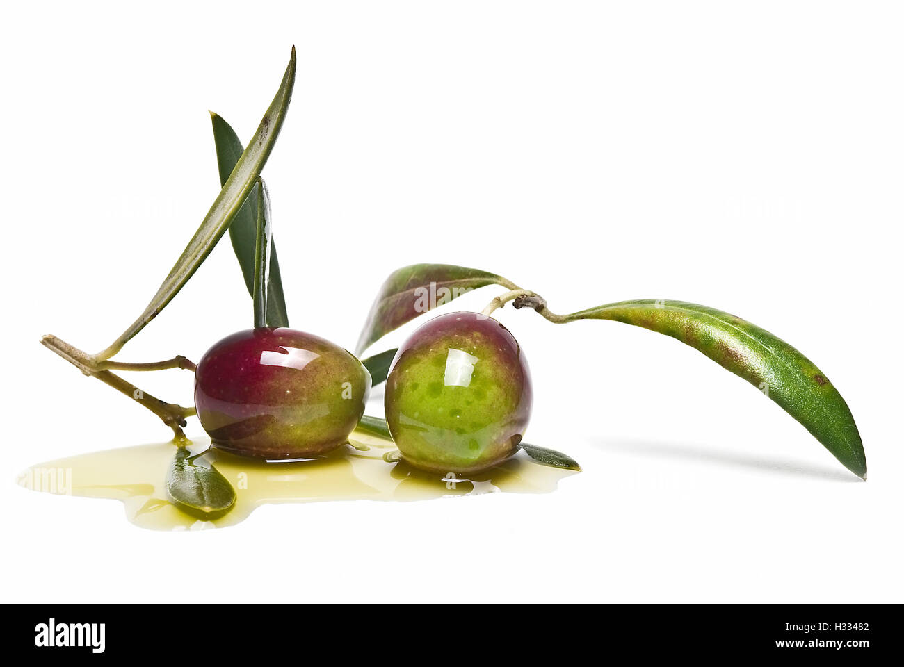 Green olives with leaves covered in olive oil and isolated over awhite ...