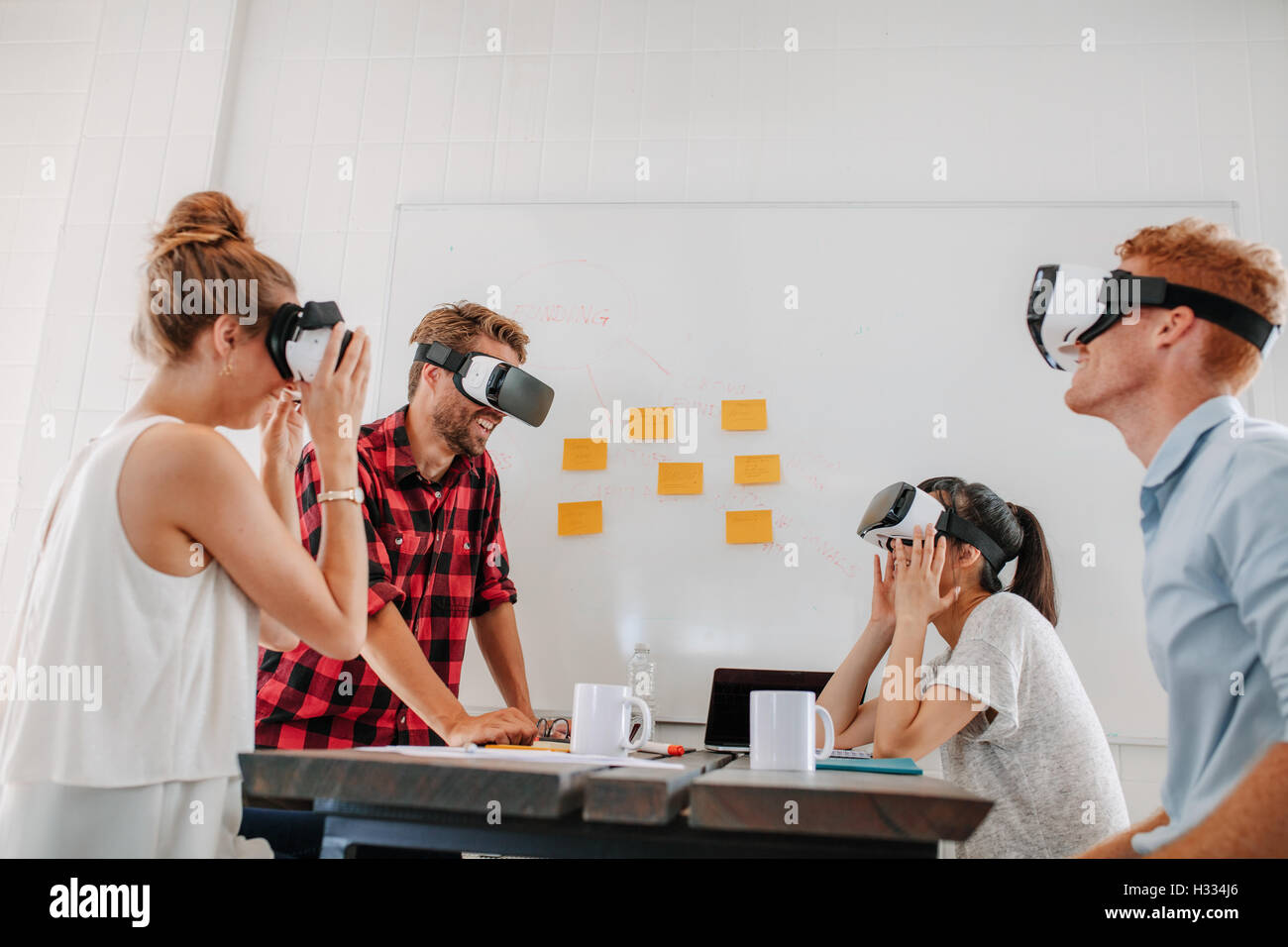Business team using virtual reality headset in office meeting. Developers meeting with virtual reality simulator around table in Stock Photo